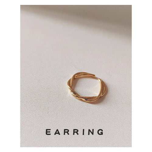 Gold twisted open band ring on textured beige surface