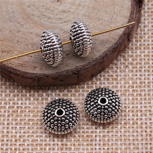 Alternate angle of dotted disc spacer beads showing domed discs covered in concentric raised dots