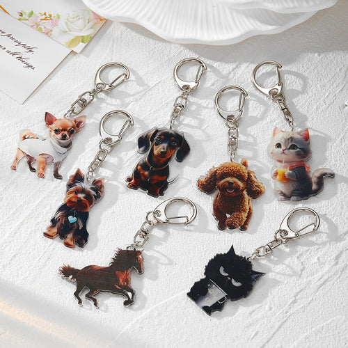 Seven acrylic animal photo keychains with silver lobster clasps on textured white