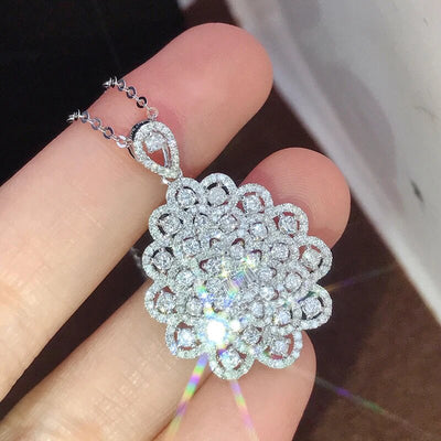 Close hand-held view of silver floral CZ pendant showing sparkle and chain