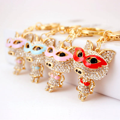 Four rhinestone pig keychains displayed with pink, blue, purple, and red masks.