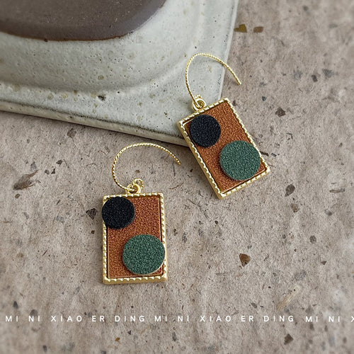 Brown fabric rectangle dangles with black green circles on stone