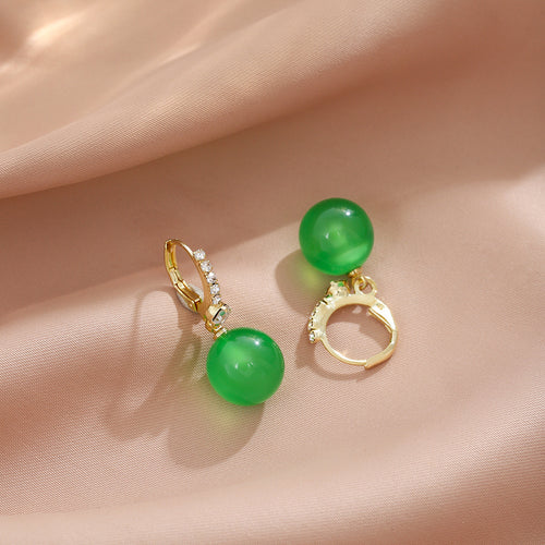 Green bead gold huggie earrings open and closed on pink satin