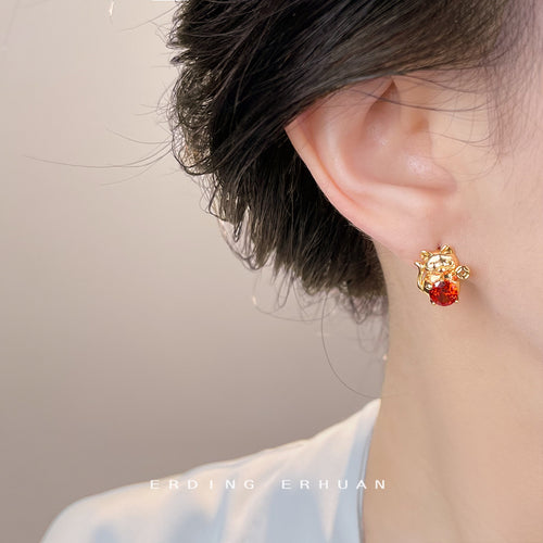 Gold lucky cat red zircon stud worn on model right ear