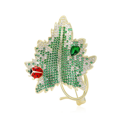 Front product view of the green crystal maple leaf accented by a red ladybug and green teardrop brooch