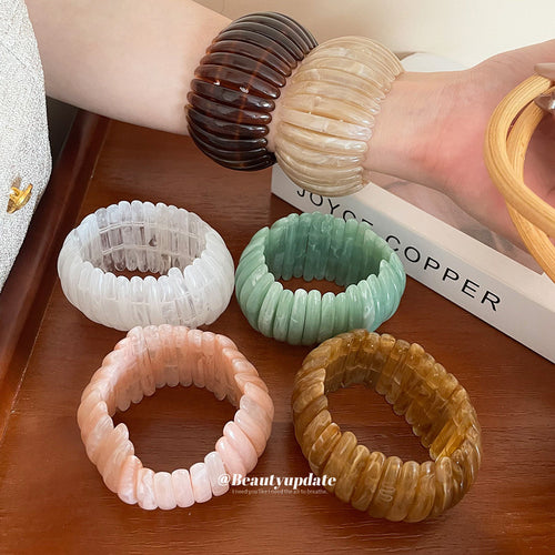 Dark and cream stretch bangles on wrist with four colors on table