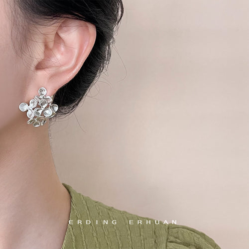 Silver-tone open-flower cluster sculpted stud earrings shown worn on an ear.
