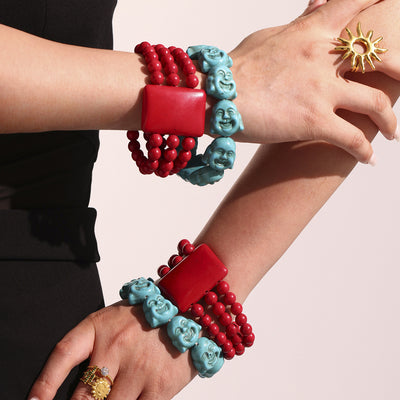 Models wrists stacked with red bead and blue Buddha bracelets