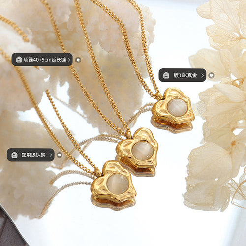 Three gold heart pendants with cat-eye stones on mirror tray