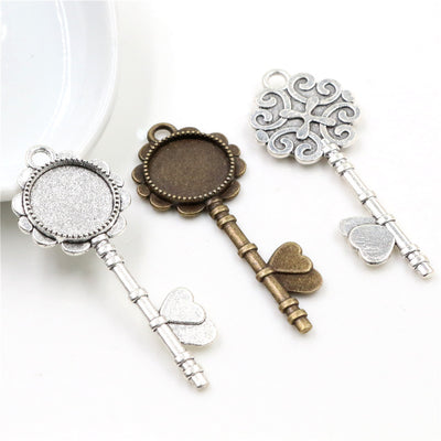 Overview of decorative key silhouettes topped by round bezel cups in silver and antique bronze tones arranged on a light