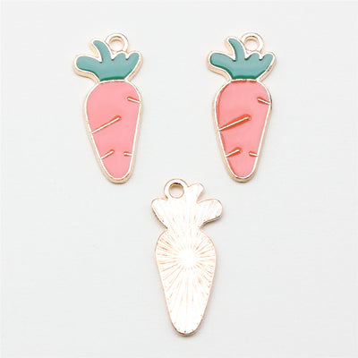 Pink carrot enamel charm shown on a hand for scale