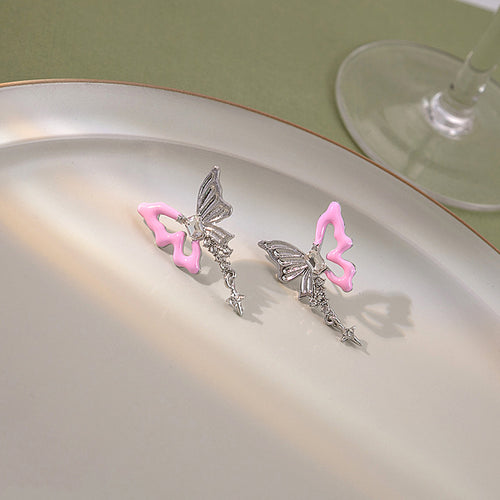 Pair of pink silver butterfly star dangle studs on ceramic plate