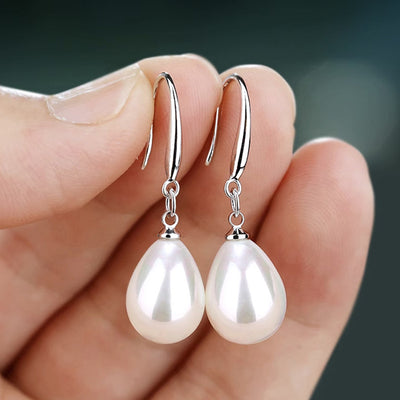 White metal teardrop pearl drops held between fingertips