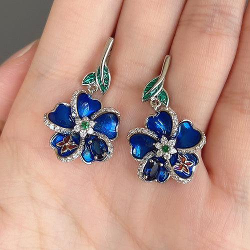 Gold Tone Blue Floral Enamel Drop Earrings with Clear Stone Accents shown in styled view