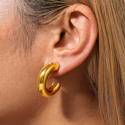 Gold chunky C-shape hollow hoop earring worn on ear close-up