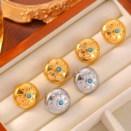 Close-up gold sun motif stud with blue center on ear