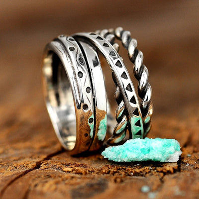 Close side view of antique silver stacked twist and stamped ring on wood