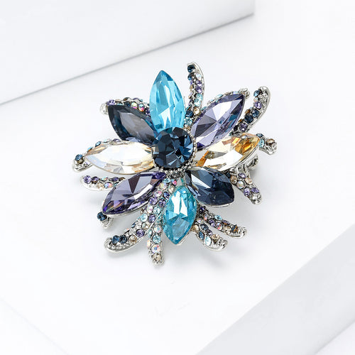 Angled display of the blue mixed crystal flower brooch with layered pointed petals