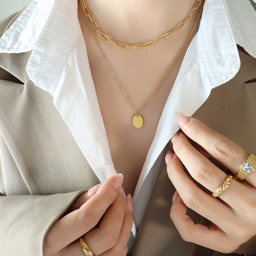 Gold paperclip choker and oval disc necklace layered on model