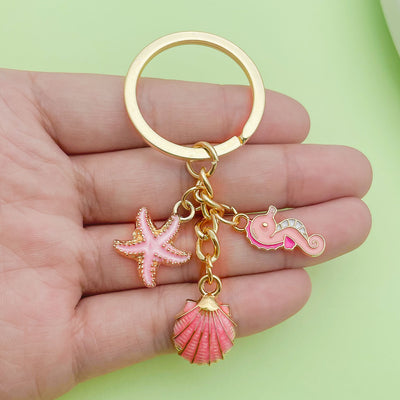 Image 1 showing a hand holding a pink and gold keychain.