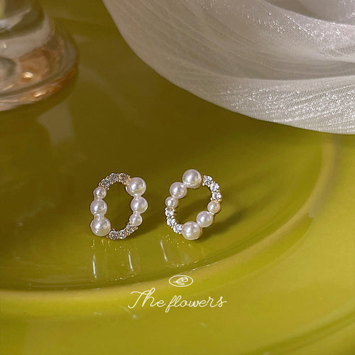 Gold oval pearl pavé studs on glossy yellow-green surface