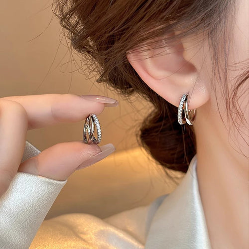 Model wearing one double-layer pave hoop and holding the matching earring