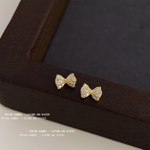 Gold-tone clear-stone tiny-bow studs in the first product display.