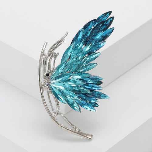 Angled display of the crystal wing brooch on a white surface