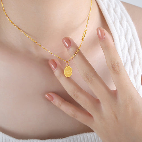 Gold oval Good Luck pendant necklace worn with hand near pendant