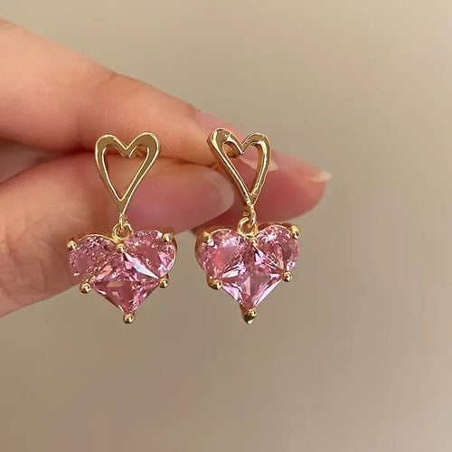 Gold open heart studs with pink heart CZ drops held in fingers