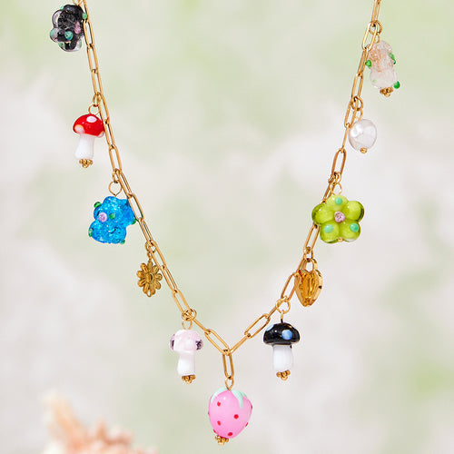 Close-up of gold paperclip chain with pink strawberry and colorful resin charms