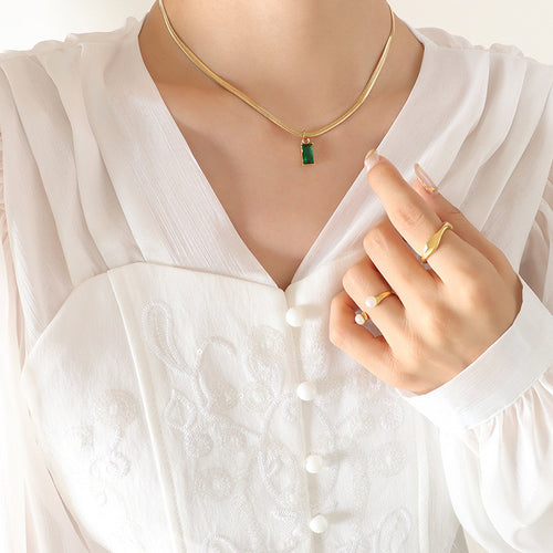 Gold snake chain emerald baguette pendant necklace worn on white blouse