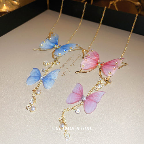 Blue and pink sheer butterfly pearl tassel necklaces on beige display tray