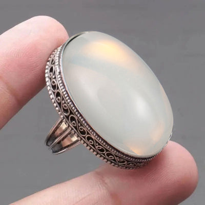 Close oval opaline ring face held in fingertips