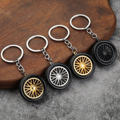 Four tire-shaped keychains show two gold-tone, one silver-tone and one black spoke rim.