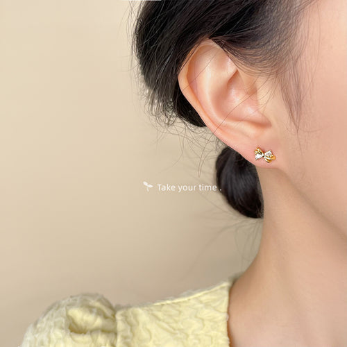 Gold mini bow stud with clear crystals worn on ear side