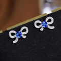 White Metal Bow Stud Earrings Blue Oval Center Pavé Stones view 5