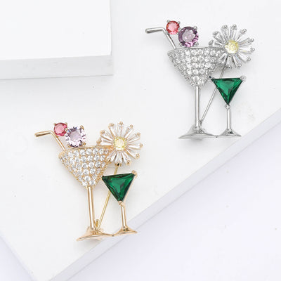 Front view of two cocktail glasses with green stones and a crystal flower garnish