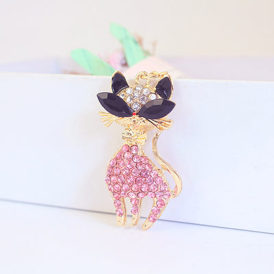Close-up of the pink rhinestone cat charm with black faceted eyes and a bow.