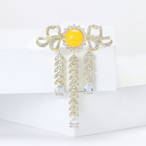 Gold bow yellow cabochon brooch on white display blocks