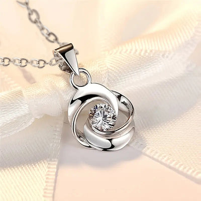 Silver interlock swirl CZ pendant close-up on cream ribbon