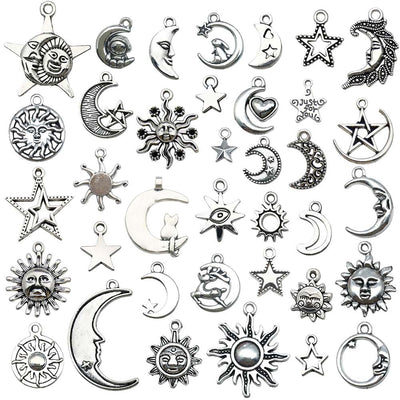 Antique silver sun and moon charms arranged on a light background