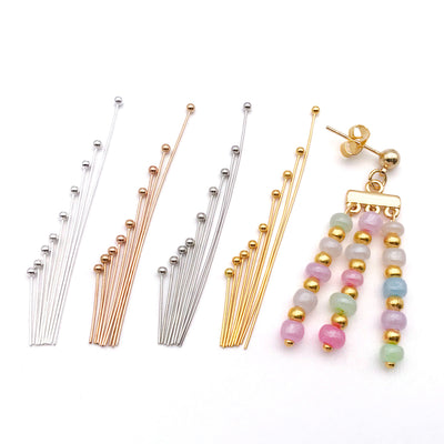 Metallic head pin jewelry findings arranged on a light background