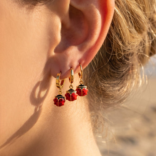 Display view of red enamel ladybug drop hoop earrings in main image 1.