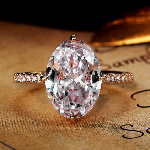 Gold-tone large oval clear CZ solitaire ring on parchment