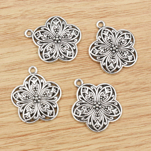 Finish comparison of openwork floral medallion metal charms with silver tone finish