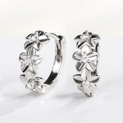 Silver floral huggie hoop earrings pair upright on white