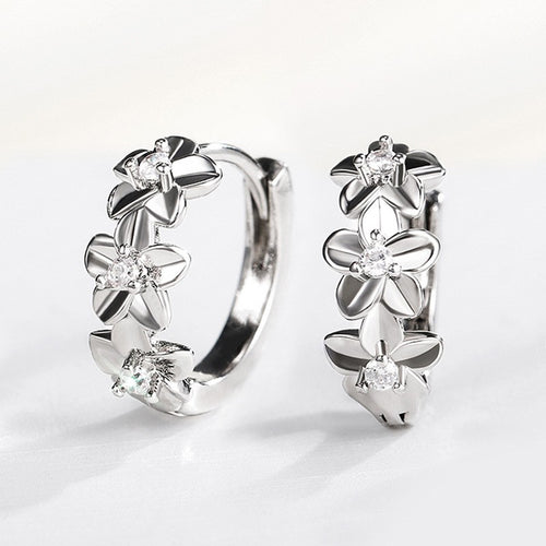 Silver floral huggie hoop earrings pair upright on white