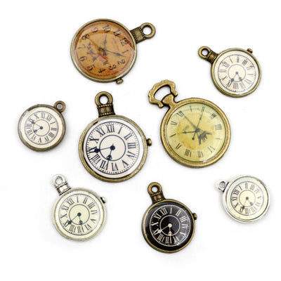 Overview of round clock-face charms with printed Roman numerals and mixed antique metal finishes arranged on a light bac