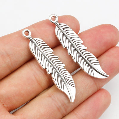 Hand held view of the long textured feather charms showing the front shape and finish